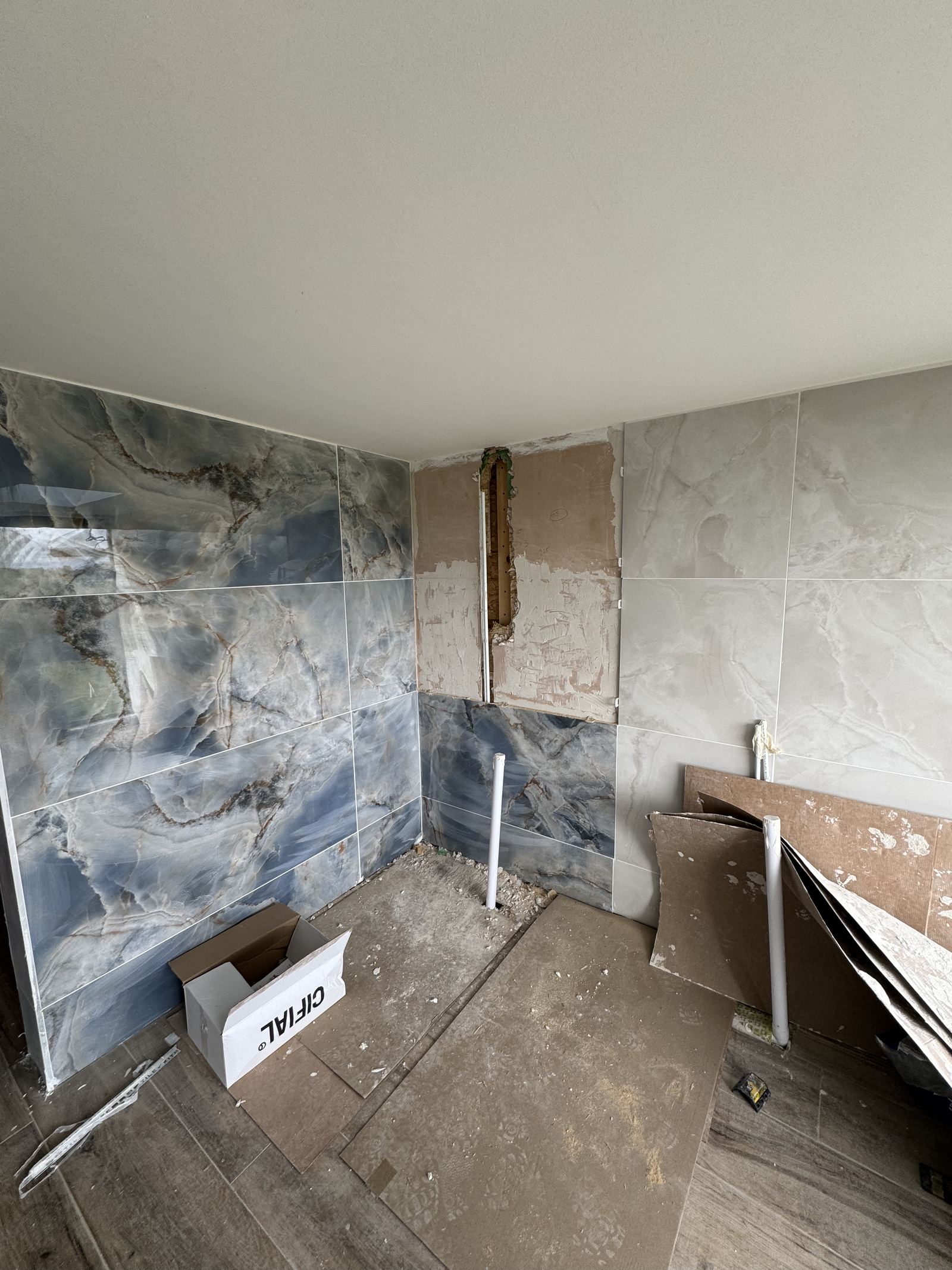 Large-format marble-effect tiles being set out on a bathroom wall