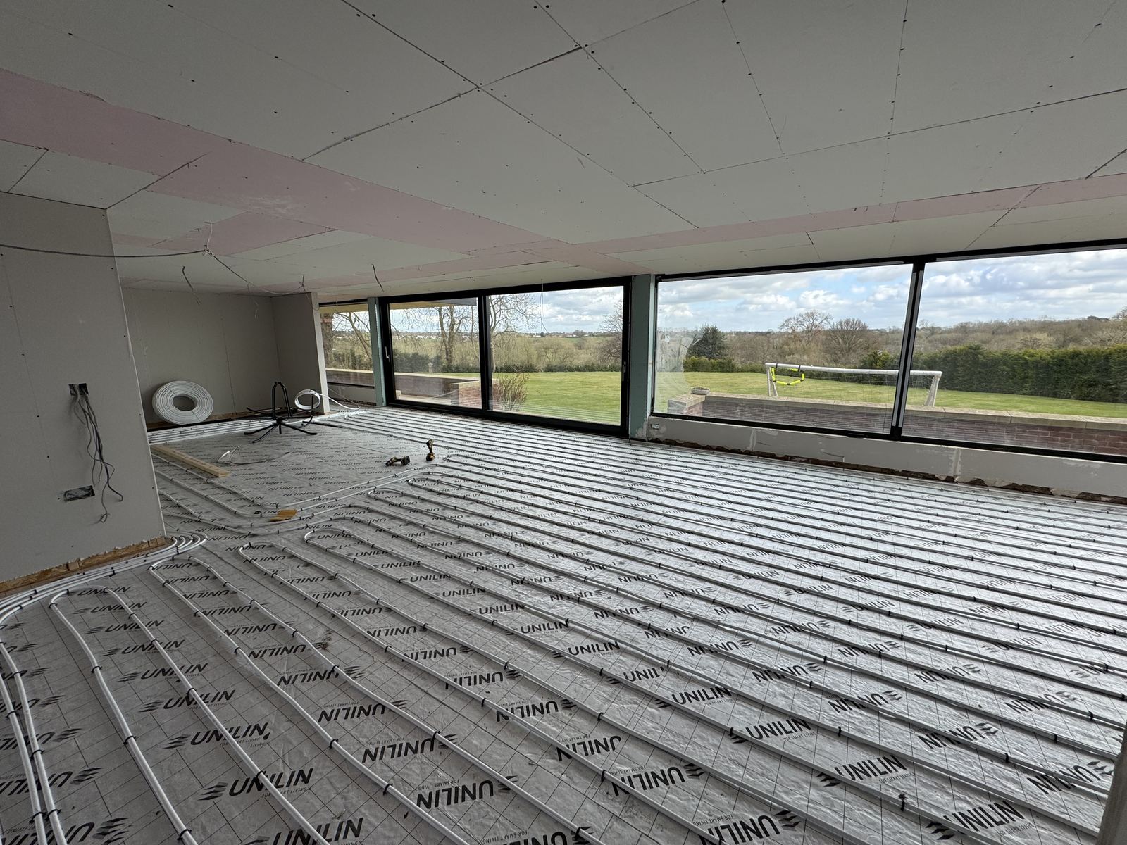 Insulation boards laid across a floor ahead of screed, beside new glazing