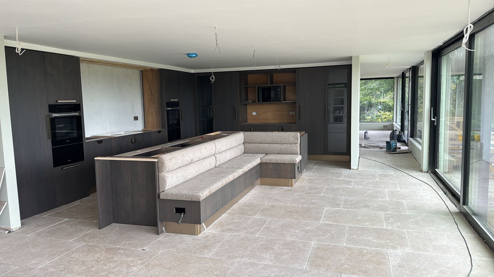 Large kitchen with dark cabinetry and stone floor, at second fix