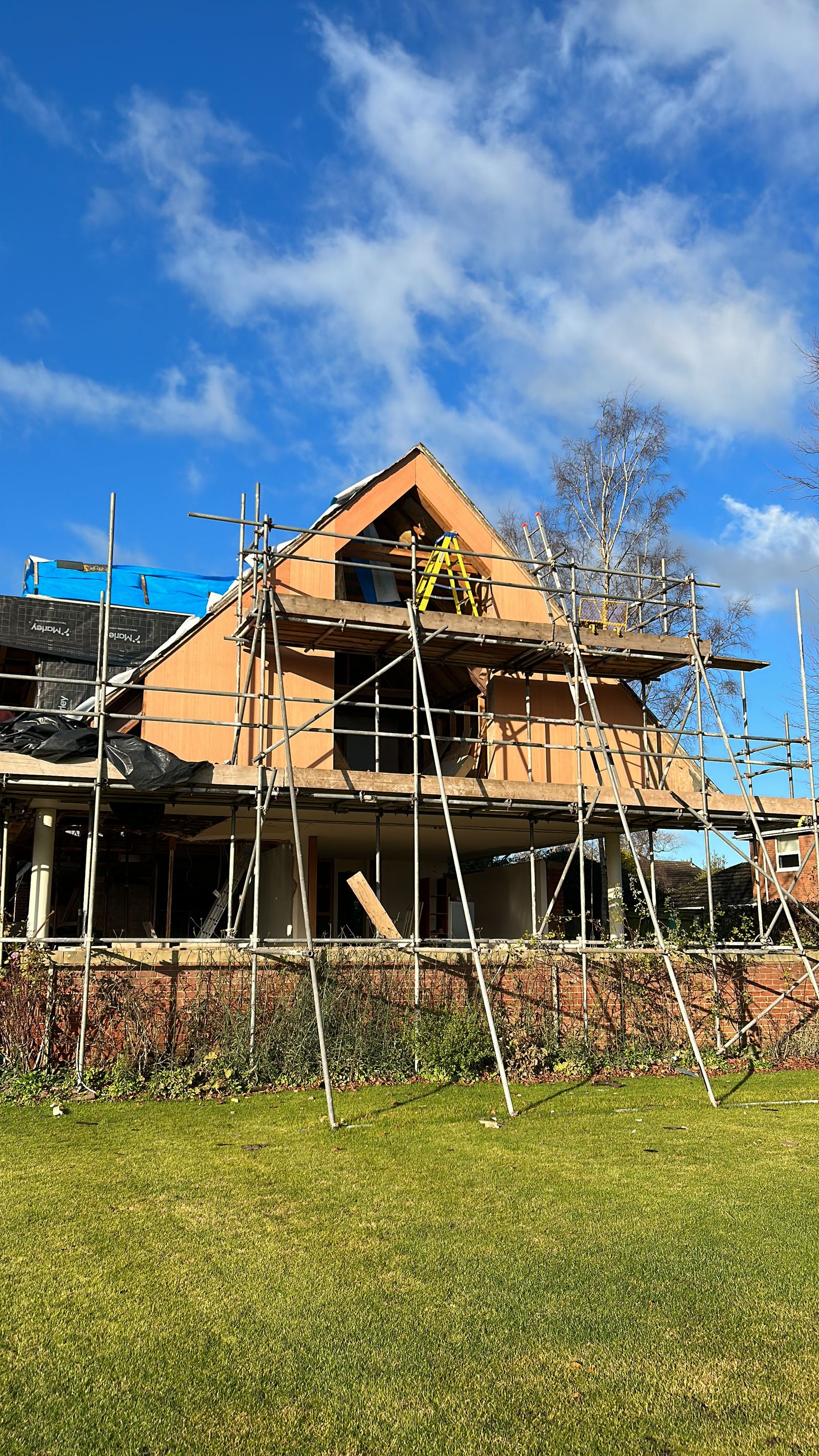 Scaffolded house with the gable opened up and new timber structure in place