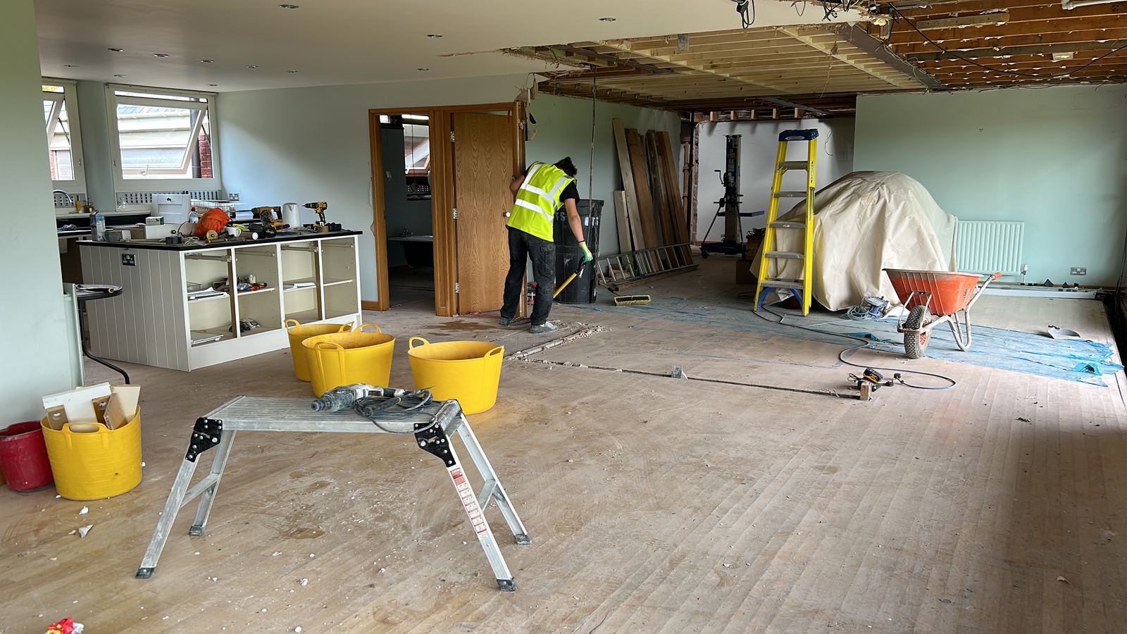 Strip-out under way inside a house, with a worker clearing the room