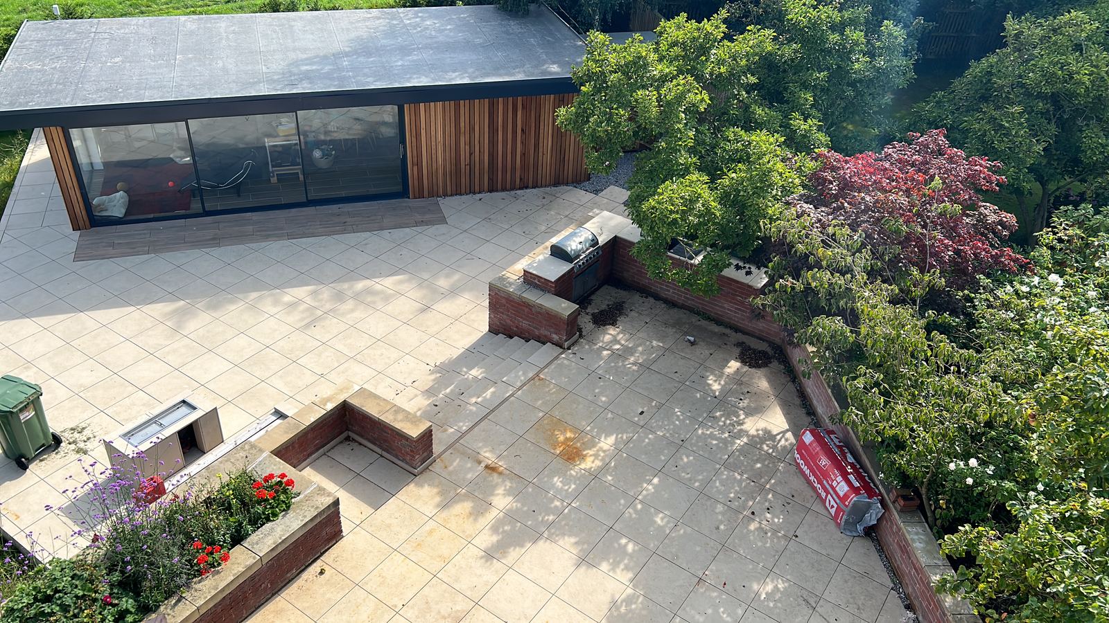 Aerial view of a finished garden room and terraced patio with planting