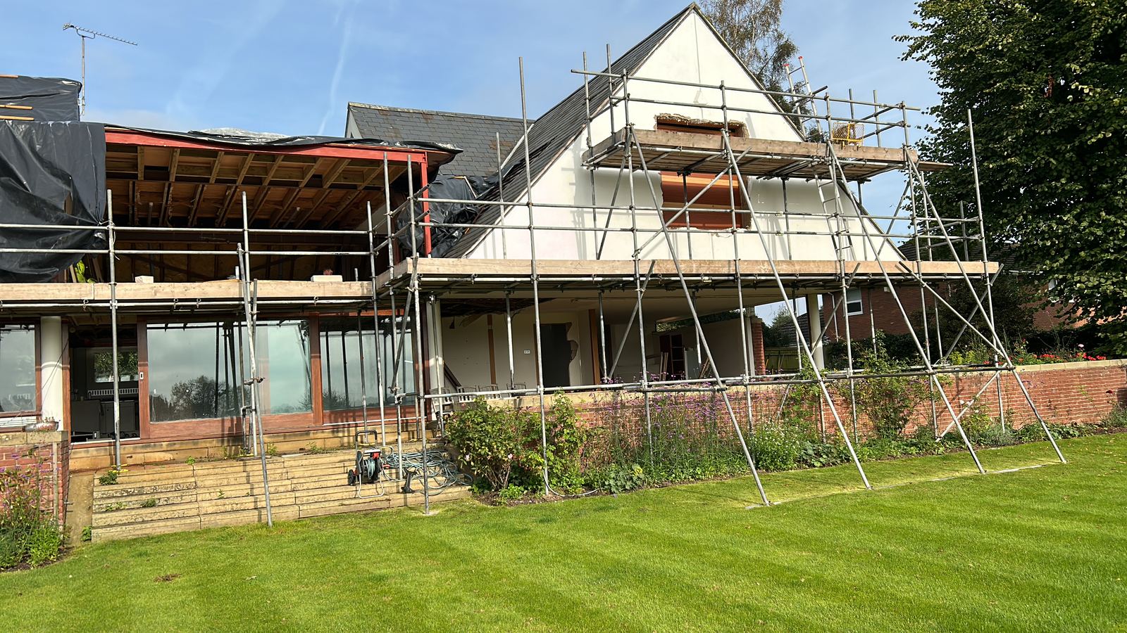 House under renovation with scaffold, roof stripped back and openings formed
